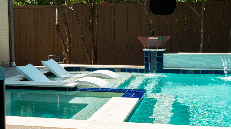 Aerial overview of a renovated infinity-edge pool with raised spa, travertine ledgestone, and cedar structure in Grapevine, TX by Selah Pools