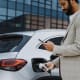 Man charging electric vehicle while looking at his phone