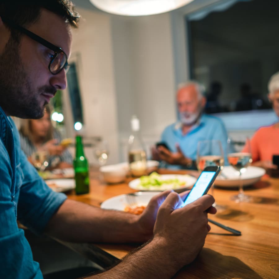 A family ignores their dinner while on their smartphones