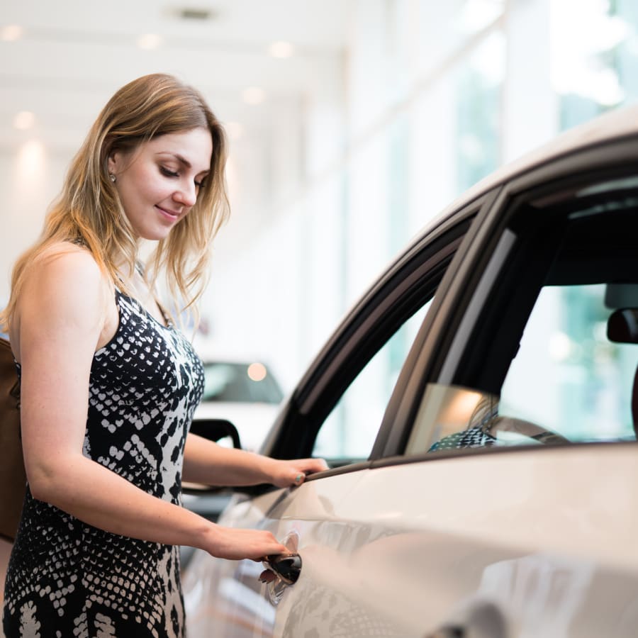 A woman stands by her car