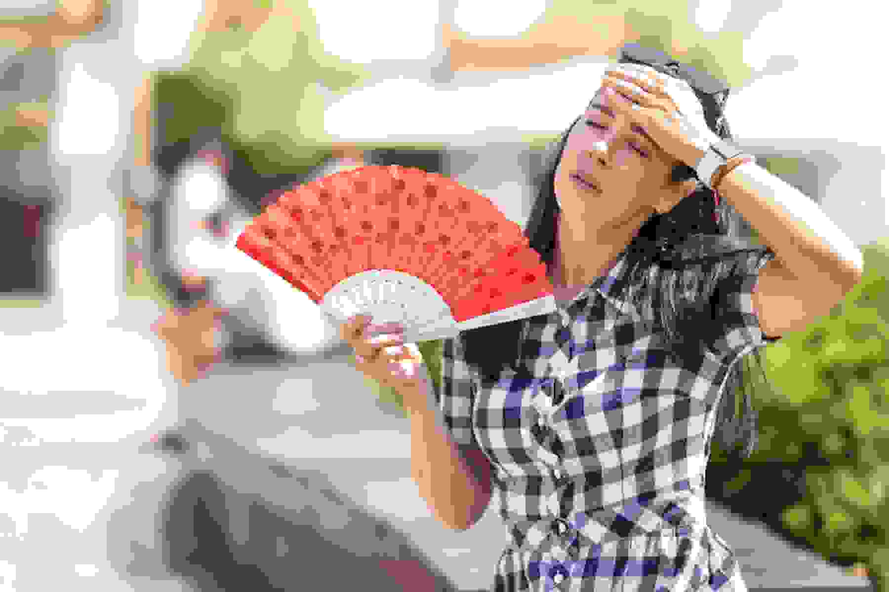 A woman fans herself in the heat.