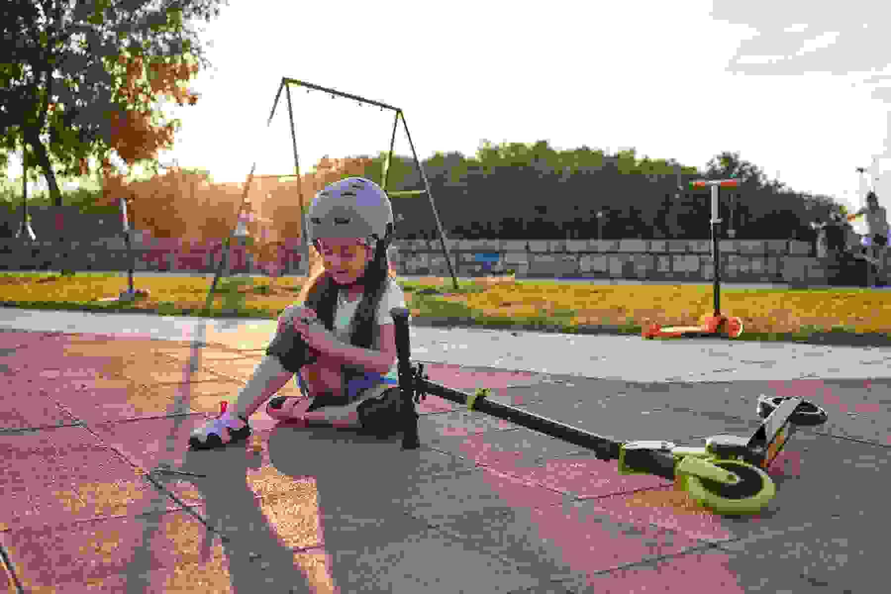 A child uses a push scooter in the park.