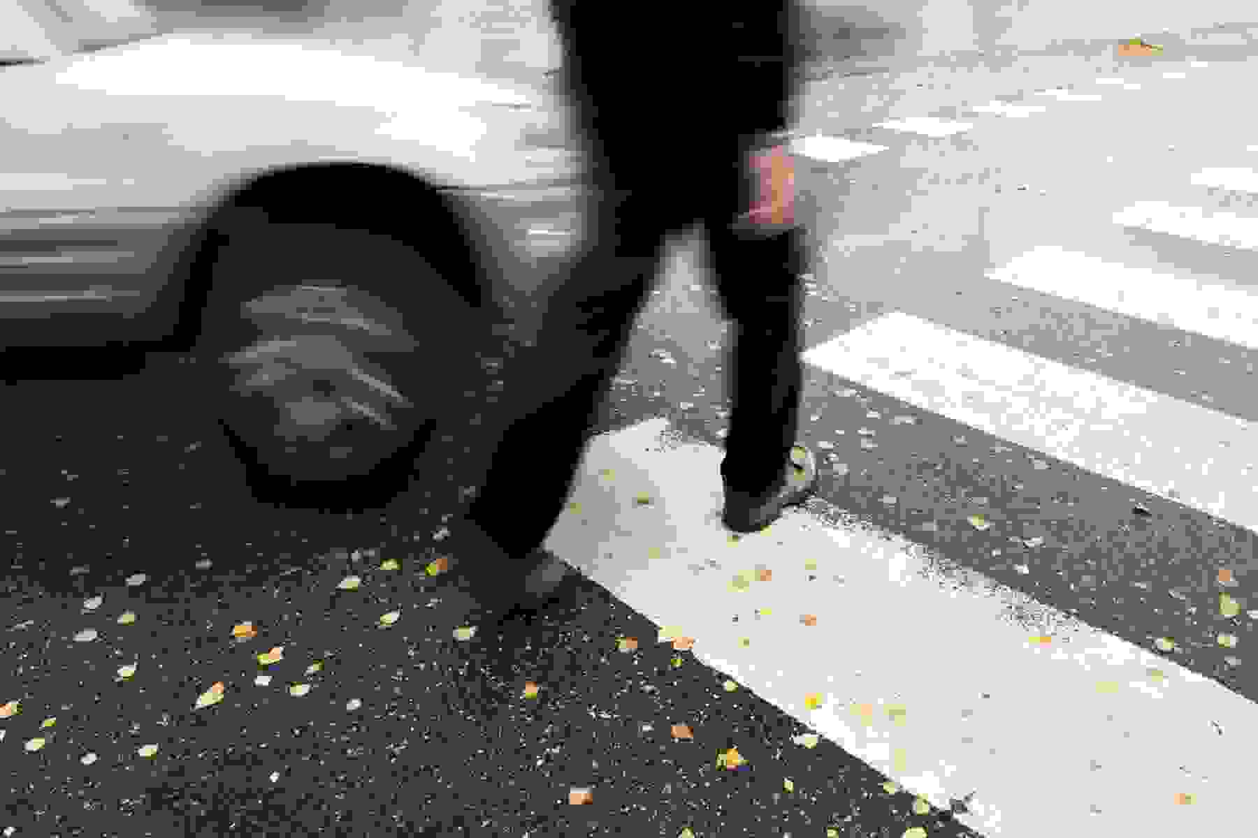 A car quickly approaches a pedestrian.