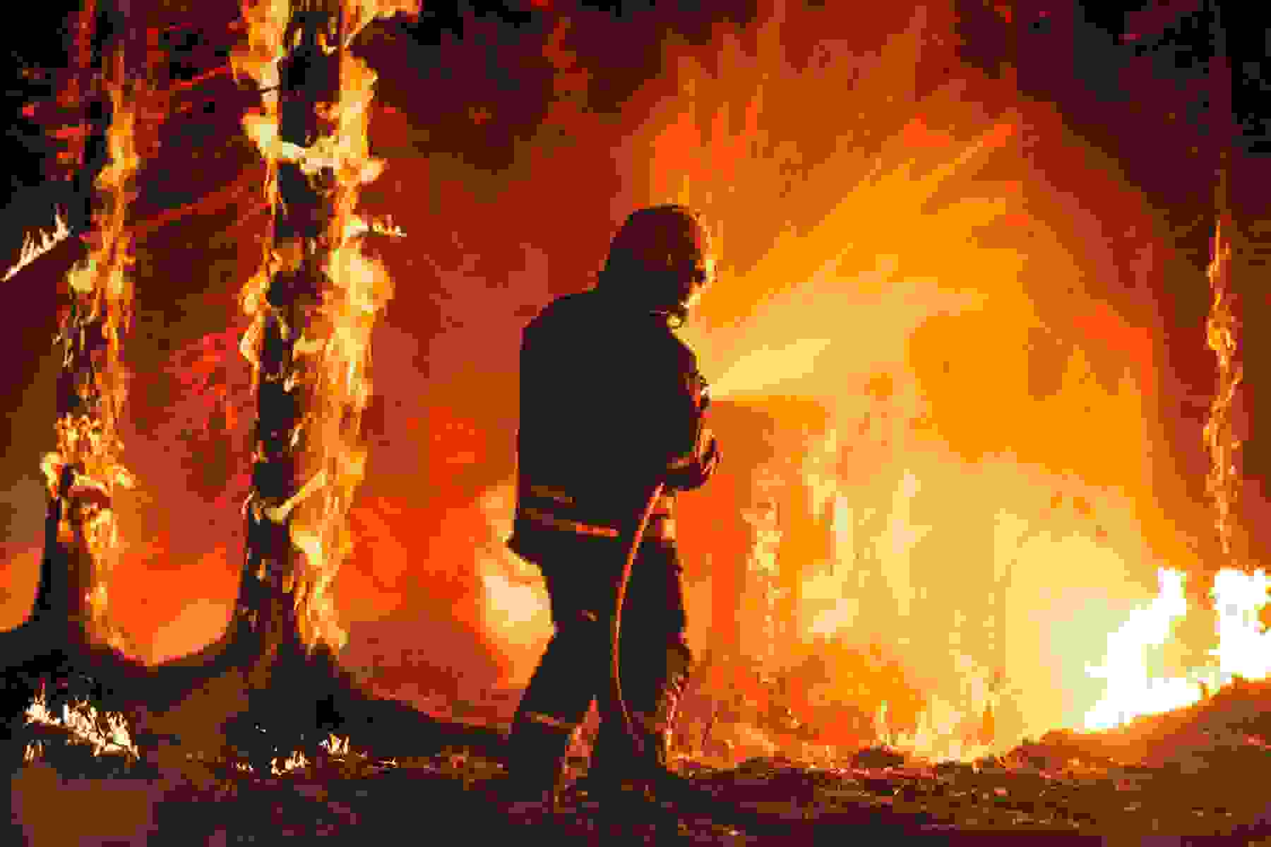 A firefighter sprays water at a wildfire.
