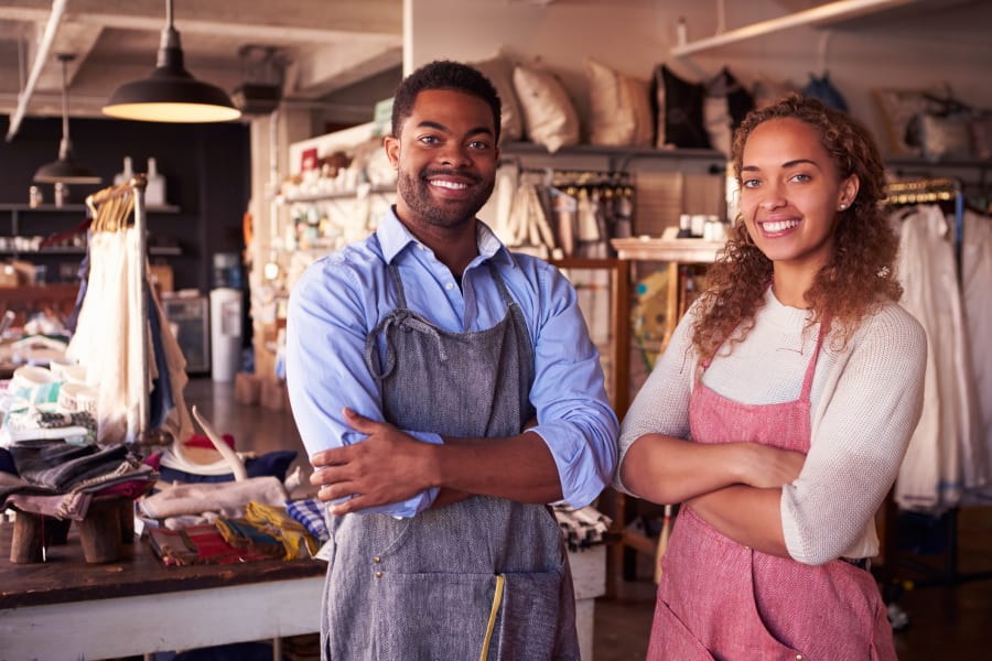 A man and woman standing in the back of a tailor's shop.