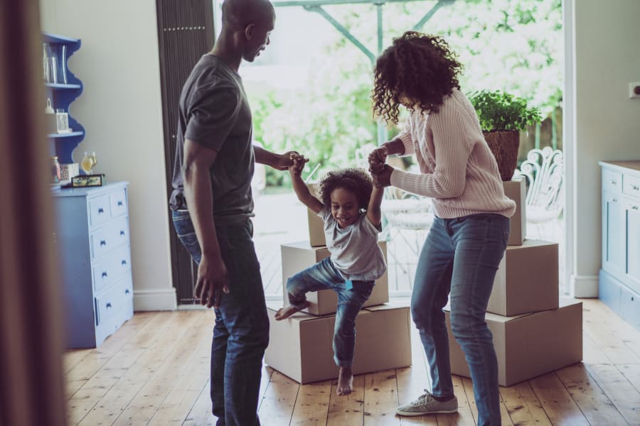 Playful parents holding son's hands in new house