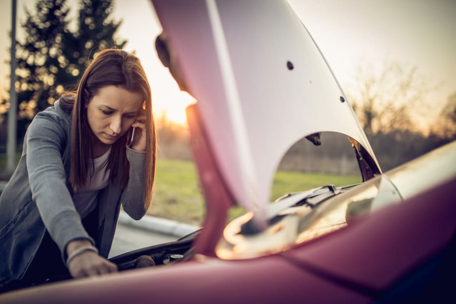 woman looking under car hood