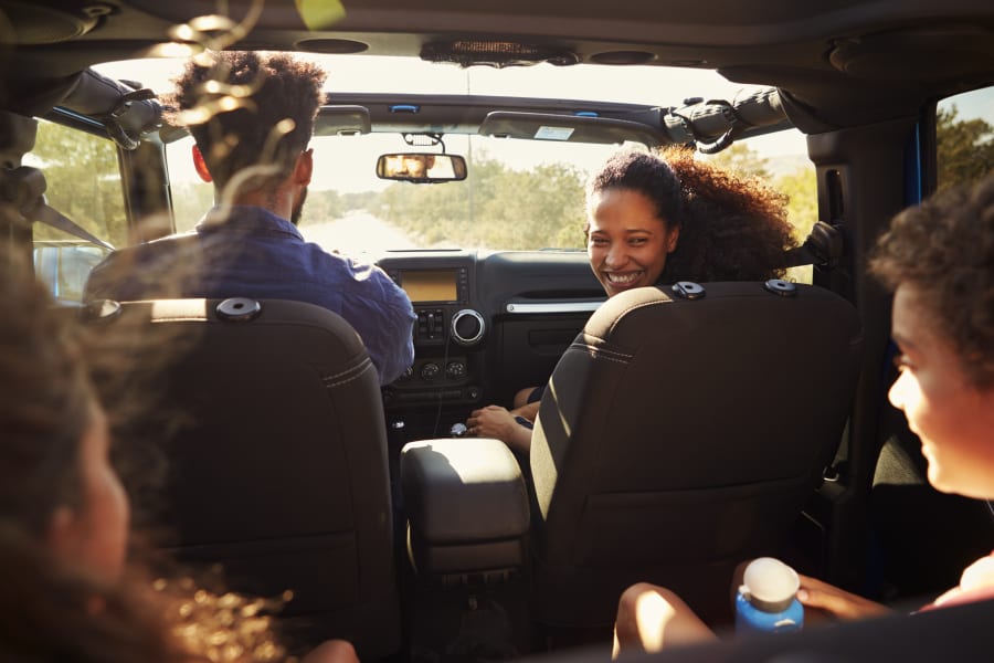 young couple driving down sunny road