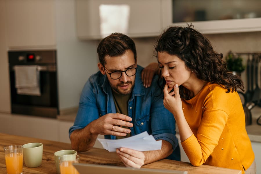 A couple looks concerned over a set of bills.