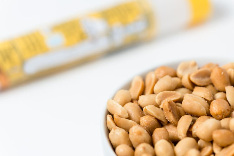 Salted peanuts in a bowl next to an allergy medication.