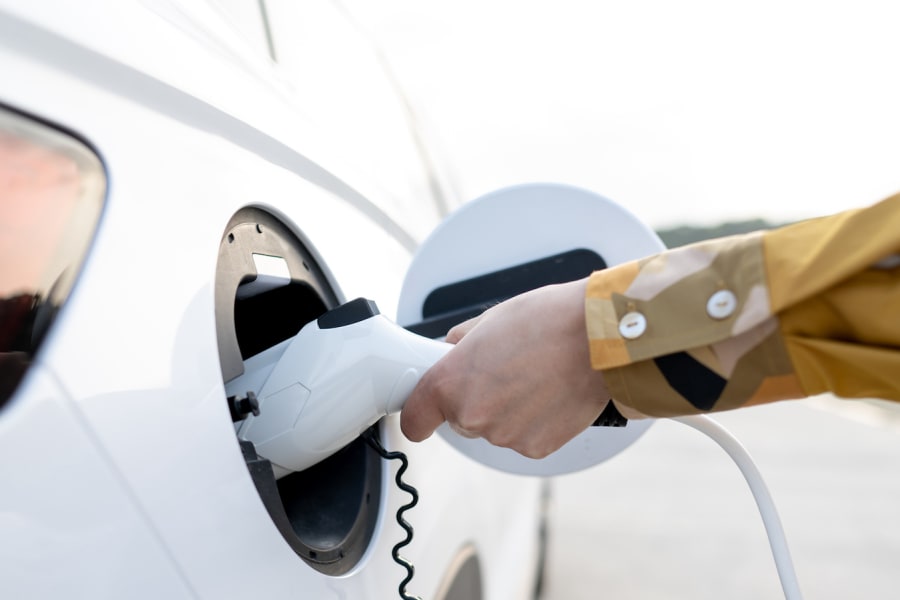 A man plugs a charger into his electric car.