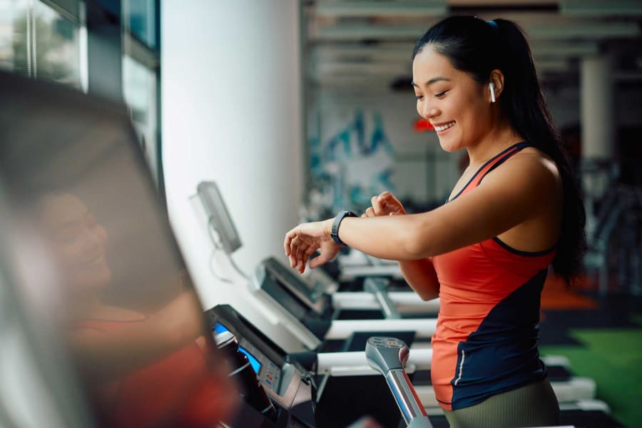 A woman checks her fitness tracker at the gym.