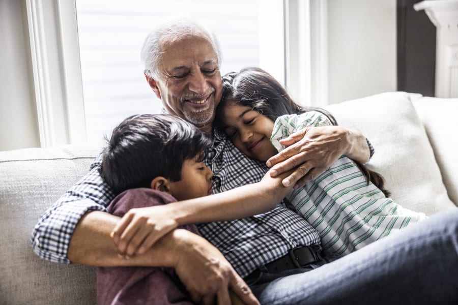 A grandfather cuddling with his grandchildren on a couch