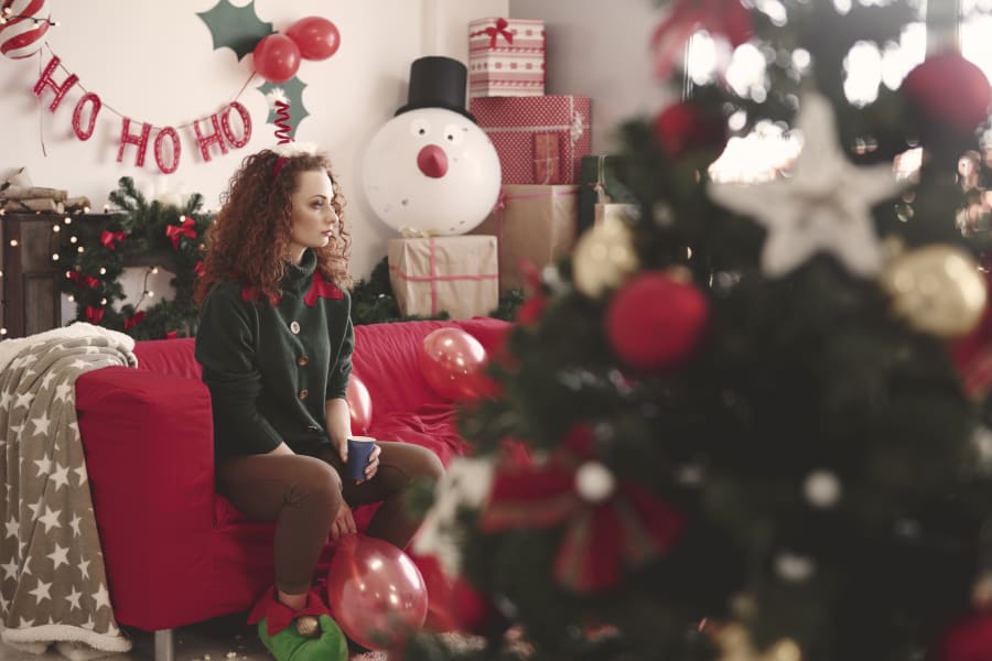 A woman sits alone on her couch at Christmas.