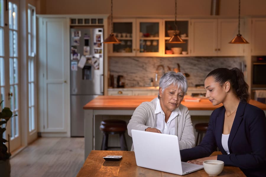 Mother and daughter reviewing documents on a laptop.