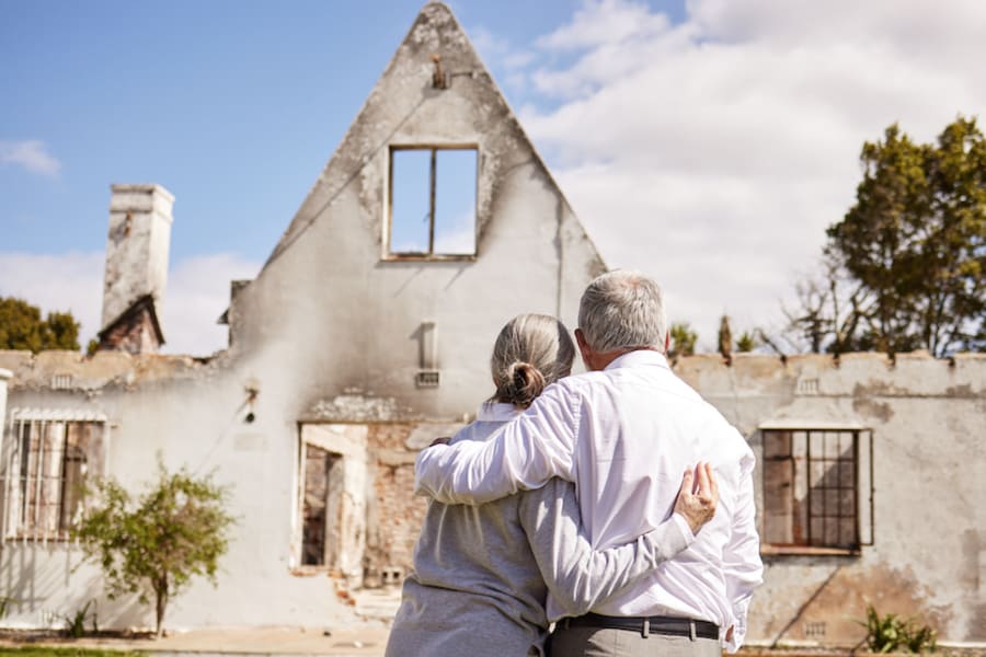 A couple looks at their damaged home.