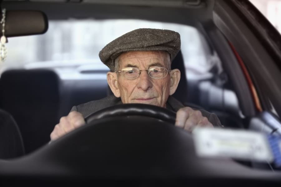 An older man drives a car.