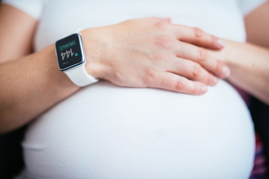 A pregnant woman wearing a smartwatch