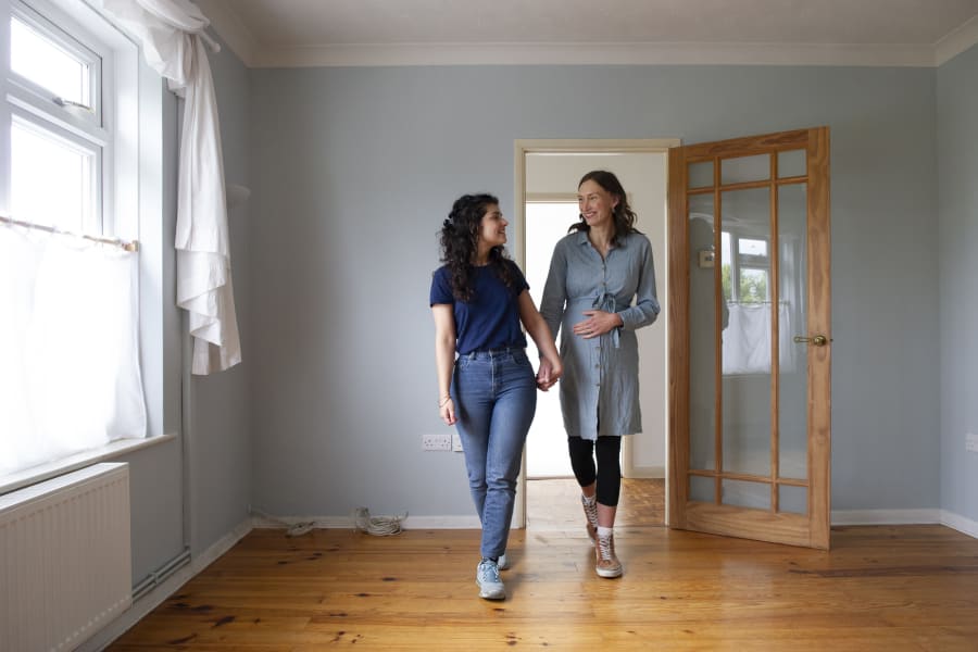 Two women walking into their house holding hands