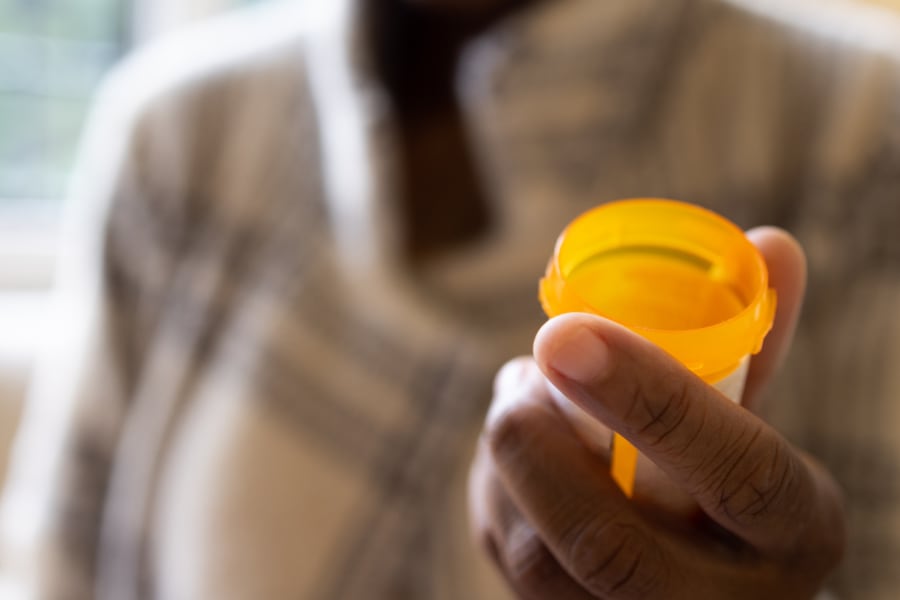 A black woman holding a prescription pill bottle