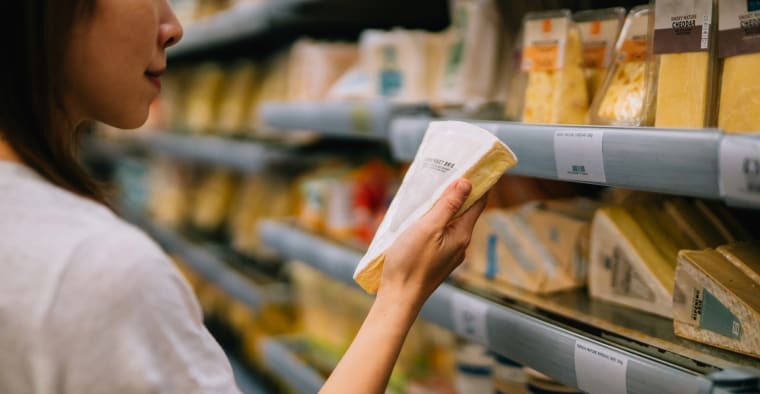Women shops for cheese at supermarket.