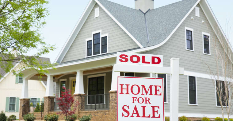 A house with a For Sale sign in the front yard