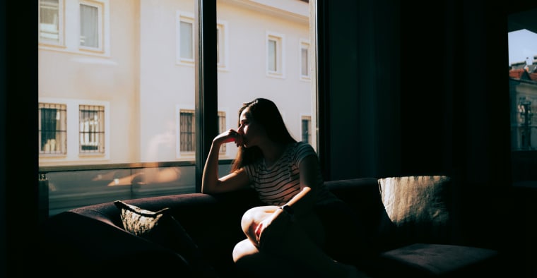 Woman stares out window sadly