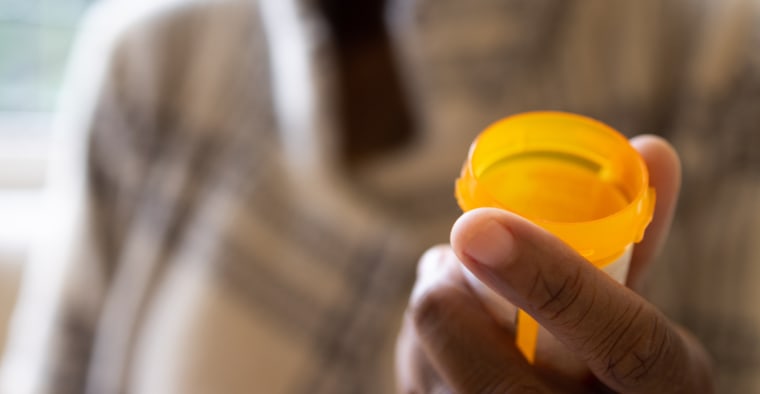 A black woman holding a prescription pill bottle