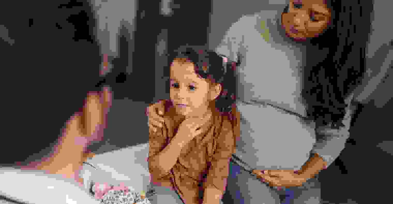 Small girl having a medical appointment with her pregnant mother at pediatricians'.