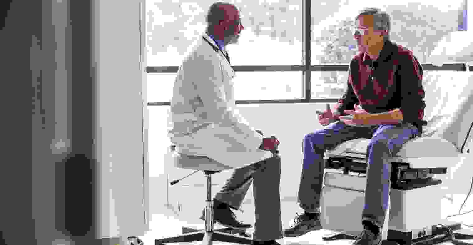 A male doctor talking with a senior male patient