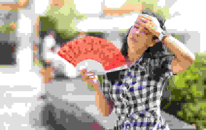 A woman fans herself in the heat.