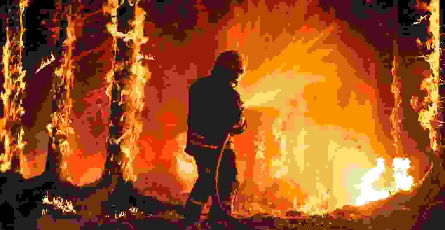 A firefighter sprays water at a wildfire.