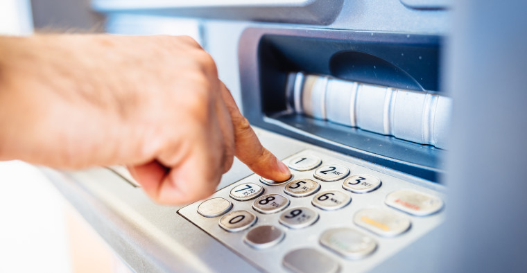 person entering pin into ATM