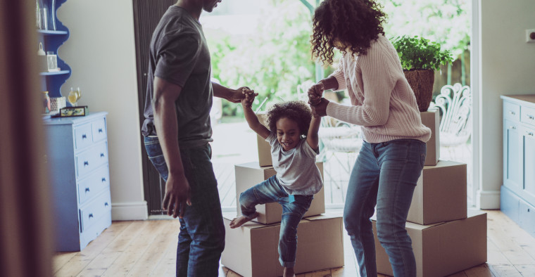 Playful parents holding son's hands in new house
