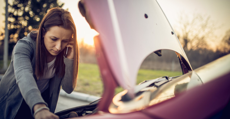 woman looking under car hood
