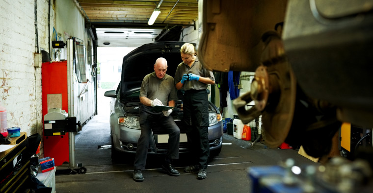 Two men fixing a car in a mechanic shop