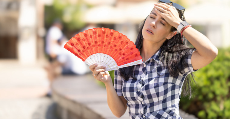A woman fans herself in the heat.