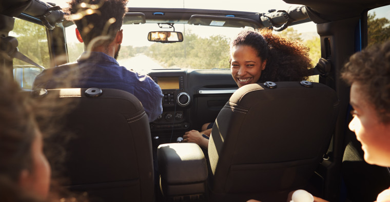 young couple driving down sunny road