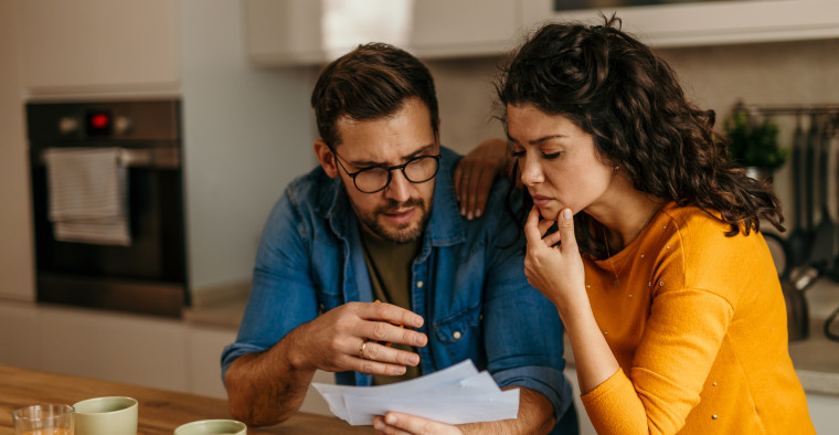 A couple looks concerned over a set of bills.