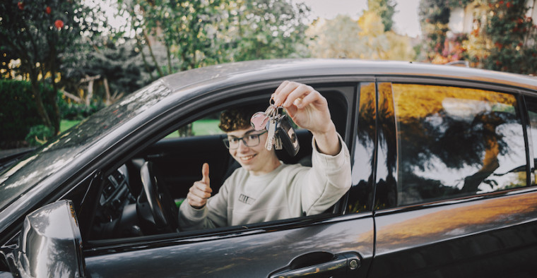 A young driver sits in his car.