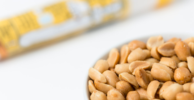 Salted peanuts in a bowl next to an allergy medication.