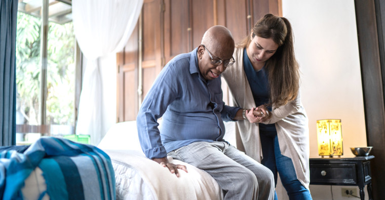 An assisted living aide helping a patient.