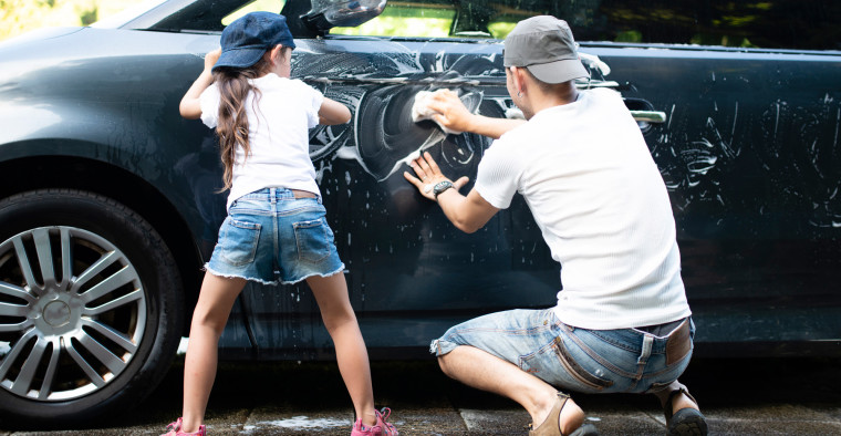 Father and daughter washing a car