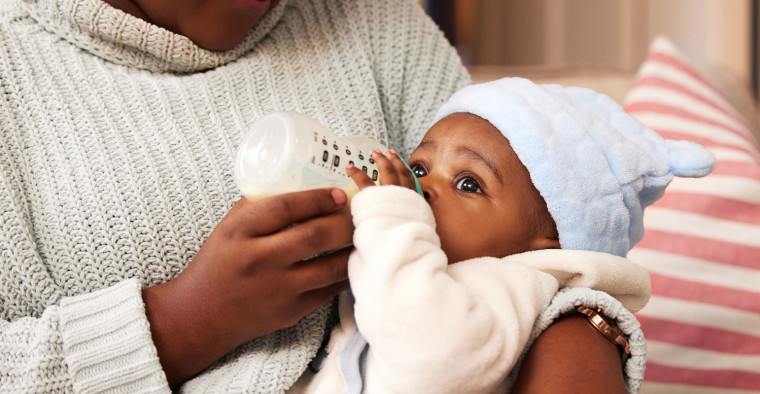 A baby drinks from a bottle.