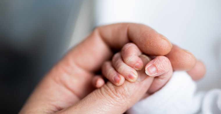 Hand of a new born baby holding a finger of their father's hand