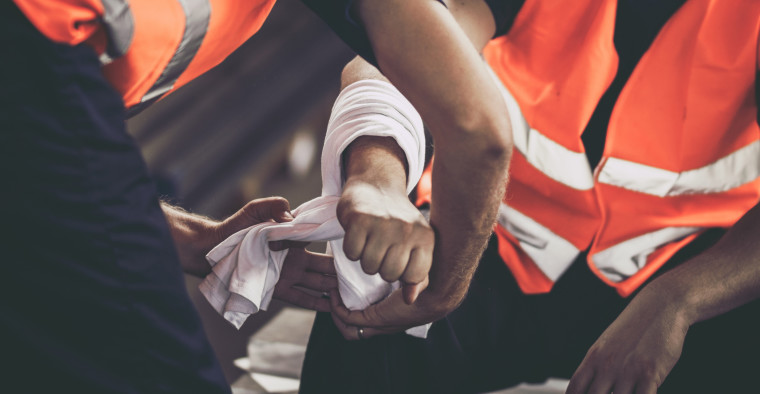 A worker assists a colleague with an injury.