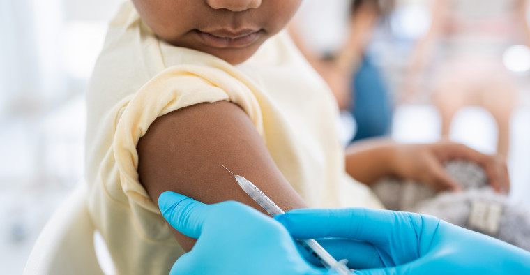 Close-up of nurse in medical gloves giving a vaccine injection to child patient.