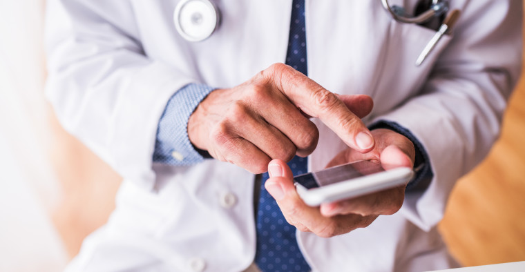 A doctor looks at his smartphone.