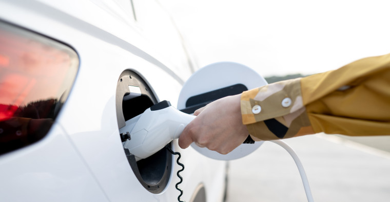 A man plugs a charger into his electric car.