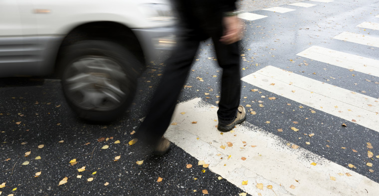 A car quickly approaches a pedestrian.